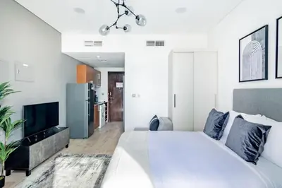 a white bedroom with a large bed and a tv at Silkhaus stunning studio in central DIFC with balcony in Dubai
