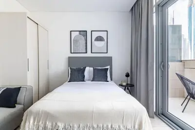 a white bedroom with a large bed and a window at Silkhaus stunning studio in central DIFC with balcony in Dubai