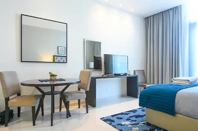 a bedroom with a table and a bed and a television at Luxury Escapes - Quiet Studio near Expo City and DWC Airport - CELESTIA TOWER in Dubai
