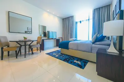 a bedroom with a bed and a table and a dining room at Luxury Escapes - Quiet Studio near Expo City and DWC Airport - CELESTIA TOWER in Dubai