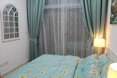a bedroom with a bed and a window with green curtains at Newly furnished One Bedroom Apartment next to Metro & Beach in Marina Residence in Dubai