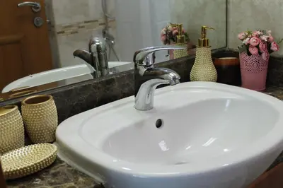 a white sink in a bathroom with vases on a counter at Newly furnished One Bedroom Apartment next to Metro & Beach in Marina Residence in Dubai