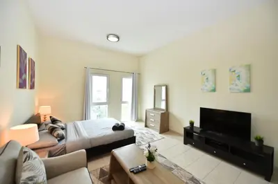 a living room with a bed and a flat screen tv at Luxury Escapes - Stylish Studio Vacation Home near Metro - MOG189 DG in Dubai