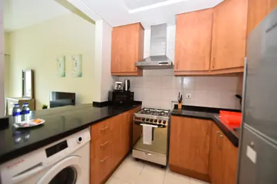 a kitchen with wooden cabinets and a washer at Luxury Escapes - Stylish Studio Vacation Home near Metro - MOG189 DG in Dubai