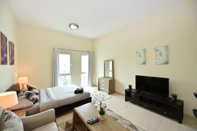 a living room with a bed and a flat screen tv at Luxury Escapes - Stylish Studio Vacation Home near Metro - MOG189 DG in Dubai