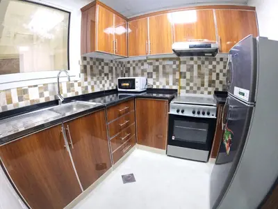 a kitchen with wooden cabinets and a stainless steel refrigerator at Karama Star Residence (Home Stay) in Dubai