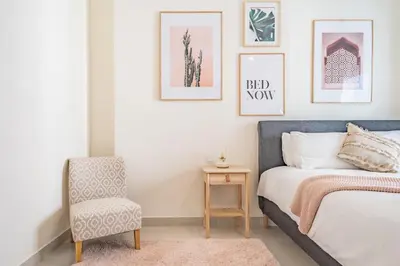 a bedroom with a bed and a chair and pictures on the wall at Stylish Waterfront Apartment With Views on Canal in Dubai