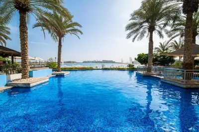 a swimming pool with palm trees and the water at Luxury Apartment Palm Jumeirah in Dubai