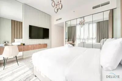 a white bedroom with a large bed and a desk at Elegant 2BR at Downtown Views Downtown Dubai by Deluxe Holiday Homes in Dubai