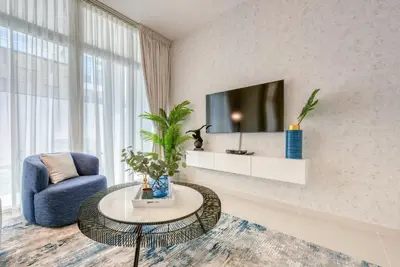 a living room with a blue chair and a tv at Spell-binding 3BR Townhouse at DAMAC Hills 2 Dubailand by Deluxe Holiday Homes in Dubai