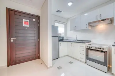 a kitchen with white cabinets and a brown door at Spell-binding 3BR Townhouse at DAMAC Hills 2 Dubailand by Deluxe Holiday Homes in Dubai