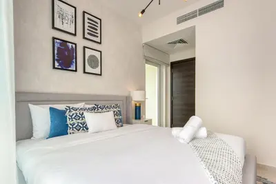 a bedroom with a white bed with blue and white pillows at Spell-binding 3BR Townhouse at DAMAC Hills 2 Dubailand by Deluxe Holiday Homes in Dubai