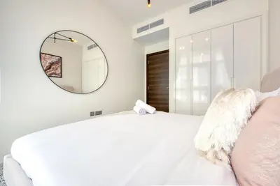 a bedroom with a white bed and a mirror at Spell-binding 3BR Townhouse at DAMAC Hills 2 Dubailand by Deluxe Holiday Homes in Dubai
