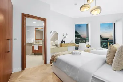 a white bedroom with a bed and a bathroom at Luxury 2BR with Skyline and Sea Views, Near Burj Khalifa & Dubai Mall in Dubai