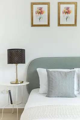 a bed with a green headboard and a table with a lamp at Frank Porter - Time Place in Dubai