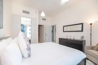 a white bedroom with a bed and a couch at Stunning 1BR with Partial Sea View in Damac Heights, Dubai Marina-21AB03 in Dubai
