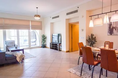a living room with a table and a dining room at Premium 4BR Apt Pool Palm Beach Club Dubai in Dubai