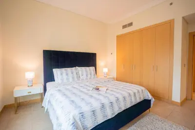a bedroom with a large bed with a blue headboard at Premium 4BR Apt Pool Palm Beach Club Dubai in Dubai