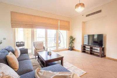 a living room with a couch and a tv at Premium 4BR Apt Pool Palm Beach Club Dubai in Dubai
