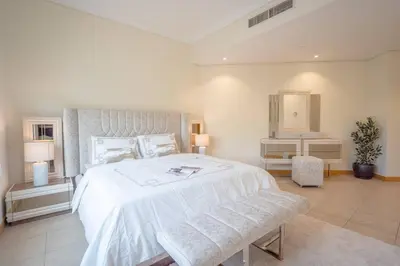 a white bedroom with a large bed and a mirror at Premium 4BR Apt Pool Palm Beach Club Dubai in Dubai