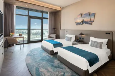 two beds in a hotel room with a large window at Paramount Hotel Midtown in Dubai