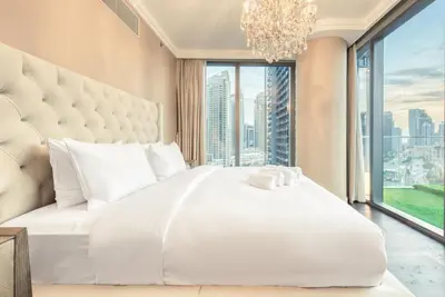 a bedroom with a large white bed with a large window at Luxurious 3 Bedroom Apartment in Boulevard Point, Connected to Dubai Mall in Dubai