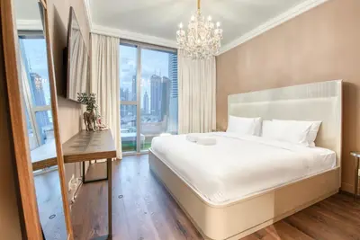 a bedroom with a large white bed and a chandelier at Luxurious 3 Bedroom Apartment in Boulevard Point, Connected to Dubai Mall in Dubai