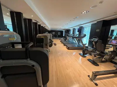 a gym with a row of treadmills and machines at Walk to Burj Khalifa from this 2BR with Skyline Balcony View in Dubai