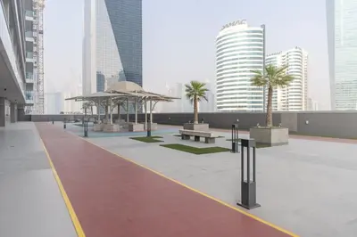 a courtyard with benches and palm trees in a city at GuestReady Holiday Homes - On The Rocks in Dubai