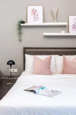 a white bed with pink pillows and a book on it at GuestReady Holiday Homes - On The Rocks in Dubai