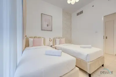 two beds in a room with white walls at Exquisite 2BR at Zahra Breeze Dubailand by Deluxe Holiday Homes in Dubai