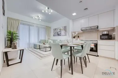 a kitchen and living room with a table and chairs at Exquisite 2BR at Zahra Breeze Dubailand by Deluxe Holiday Homes in Dubai