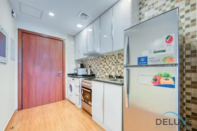 a kitchen with a refrigerator and a stove at Short Distance from Global Village & Other Major Attractions Studio Unit, Al Jawhara Tower, Jumeirah Village Triangle by Deluxe Holiday Homes in Dubai