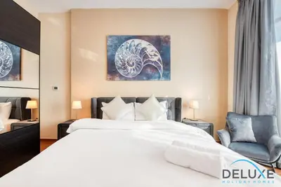 a hotel room with a bed and a chair at Short Distance from Global Village & Other Major Attractions Studio Unit, Al Jawhara Tower, Jumeirah Village Triangle by Deluxe Holiday Homes in Dubai