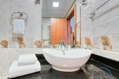 a white bathroom with a sink and a mirror at Short Distance from Global Village & Other Major Attractions Studio Unit, Al Jawhara Tower, Jumeirah Village Triangle by Deluxe Holiday Homes in Dubai