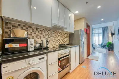 a kitchen with a washer and dryer in it at Short Distance from Global Village & Other Major Attractions Studio Unit, Al Jawhara Tower, Jumeirah Village Triangle by Deluxe Holiday Homes in Dubai