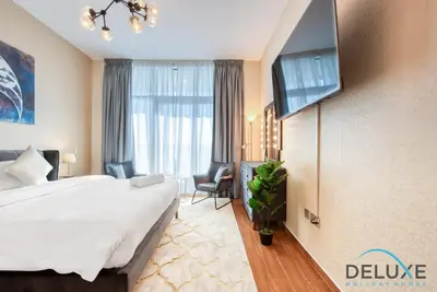 a hotel room with a bed and a tv at Short Distance from Global Village & Other Major Attractions Studio Unit, Al Jawhara Tower, Jumeirah Village Triangle by Deluxe Holiday Homes in Dubai