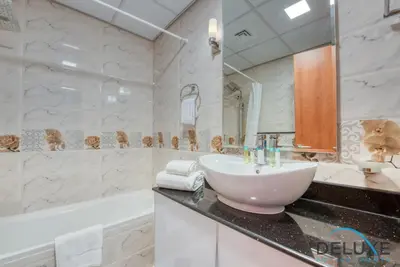 a white bathroom with a sink and a bath tub at Short Distance from Global Village & Other Major Attractions Studio Unit, Al Jawhara Tower, Jumeirah Village Triangle by Deluxe Holiday Homes in Dubai