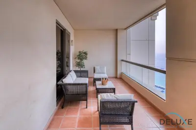 a balcony with chairs and a couch and a table at High-floor 1BR Unit Close to Beach with Sea Views, Sadaf 6, Jumeirah Beach Residence by Deluxe Holiday Homes in Dubai