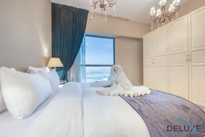 a bedroom with a large white bed with a window at High-floor 1BR Unit Close to Beach with Sea Views, Sadaf 6, Jumeirah Beach Residence by Deluxe Holiday Homes in Dubai