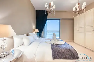 a bedroom with a large white bed with a large window at High-floor 1BR Unit Close to Beach with Sea Views, Sadaf 6, Jumeirah Beach Residence by Deluxe Holiday Homes in Dubai