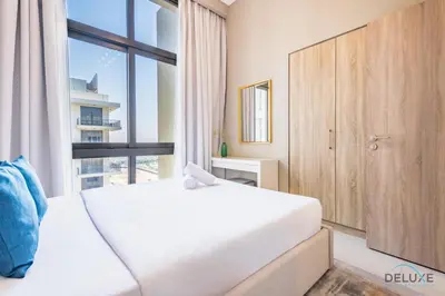 a bedroom with a large white bed and a window at Charming 2BR at Rawda Parkview Town Square Dubailand by Deluxe Holiday Homes in Dubai