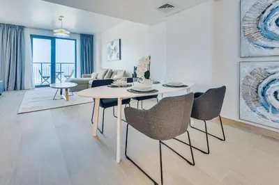 a dining room and living room with a table and chairs at Lovely sea view apt La Cote 1 La Mer 1min to beach in Dubai