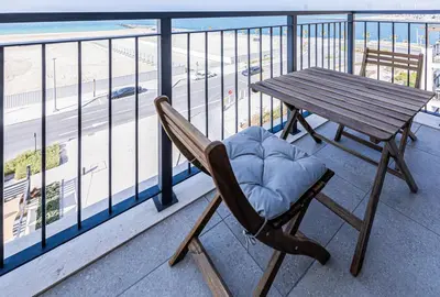 a wooden chair sitting on a balcony with a table at Lovely sea view apt La Cote 1 La Mer 1min to beach in Dubai