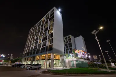 a tall white building with a parking lot at night at Emirates Sports Hotel, Dubai Sports City in Dubai