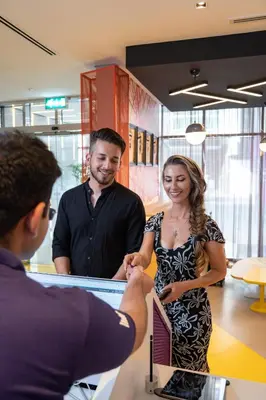 a man and a woman standing at a counter at Studio M Al Barsha Hotel by Millennium in Dubai