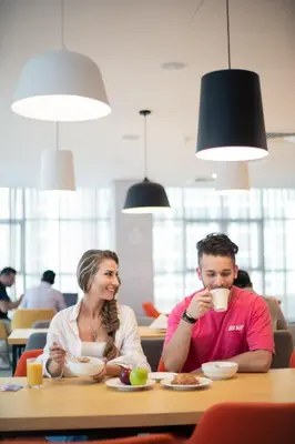 a man and woman sitting at a table with a cup of coffee at Studio M Al Barsha Hotel by Millennium in Dubai