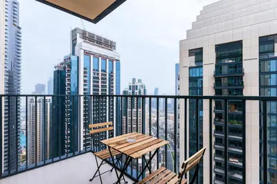 a balcony with a wooden table and chairs and buildings at Spacious & Full of light 3BR+ kids Dubai Mall in Dubai