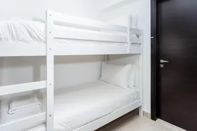 a white bunk bed in a room with a door at Lovely & Pristine 2BR + kids - 7min to Dubai Mall in Dubai