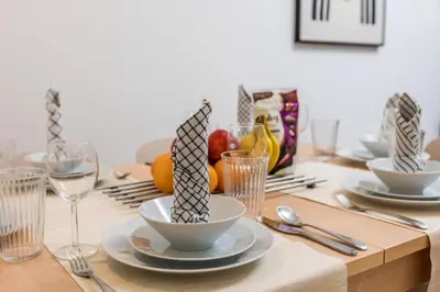 a wooden table with plates and bowls and wine glasses at Lovely & Pristine 2BR + kids - 7min to Dubai Mall in Dubai